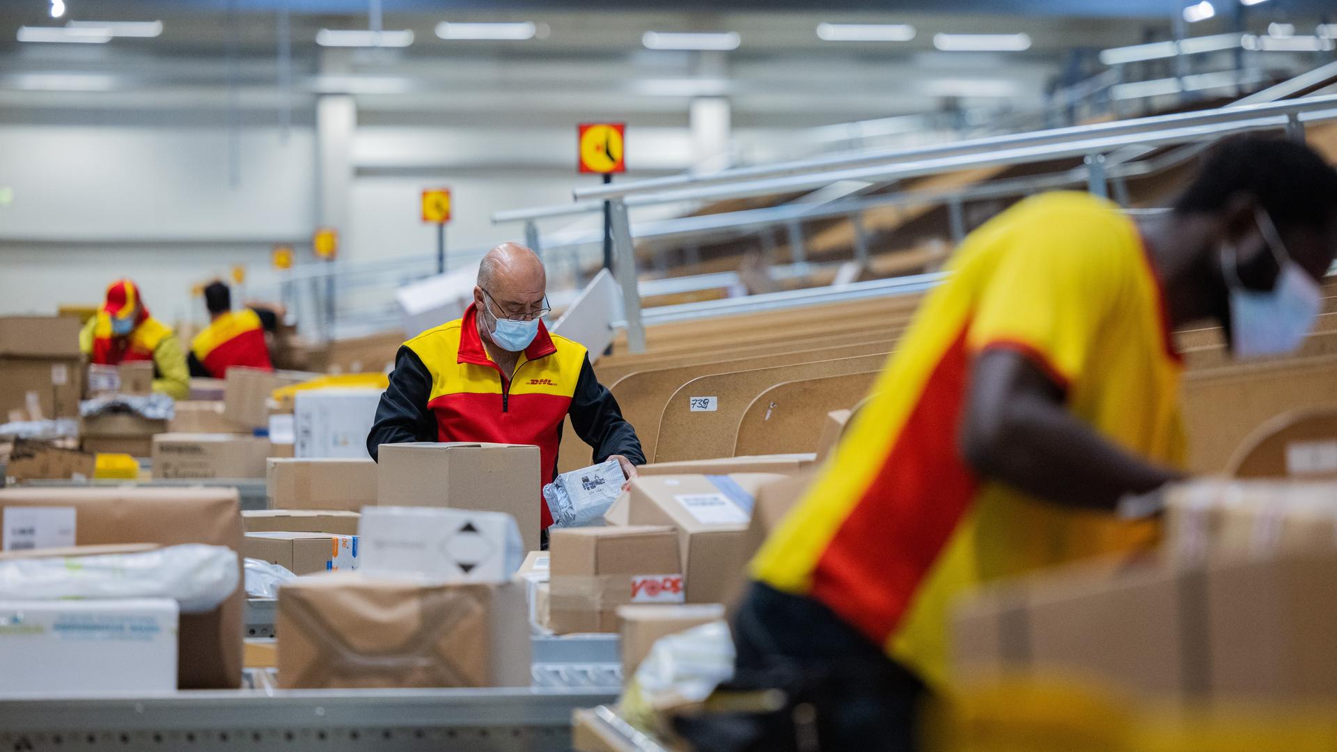 Paketzusteller sortieren und räumen in einer Zustellbasis von Deutsche Post DHL Pakete in ein Zustellfahrzeug. Viele Arbeitnehmer sind in den unteren Lohngruppen eingruppiert.