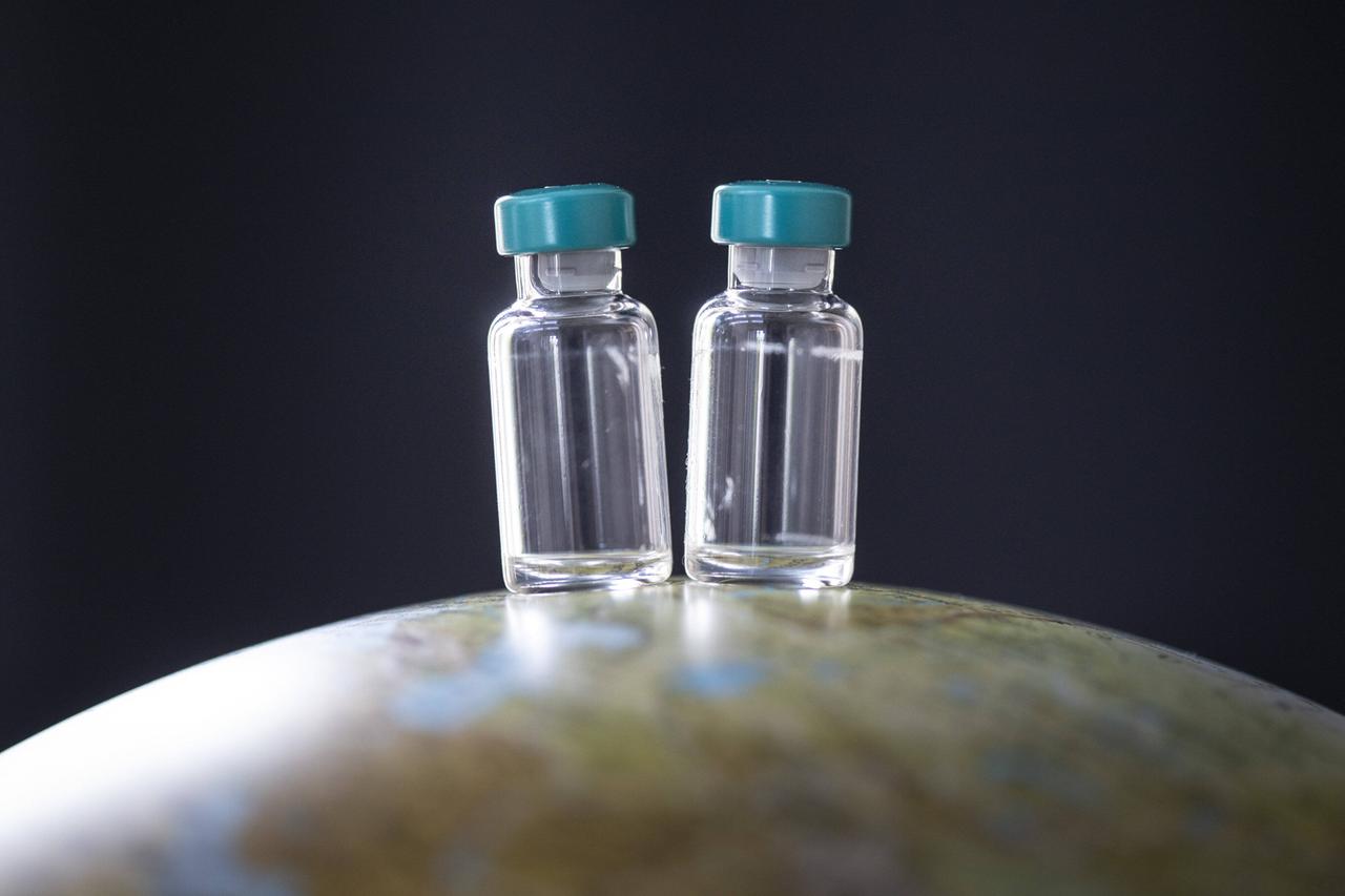 Impdosen mit unbestimmten Impfstoff stehen auf einem Globus Impdosen mit unbestimmten Impfstoff stehen auf einem Globus