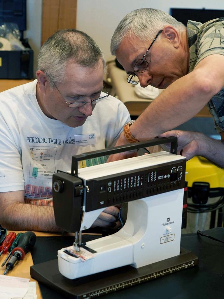 Zwei Mitarbeiter eines Repair-Cafes reparieren eine Nähmaschine.
