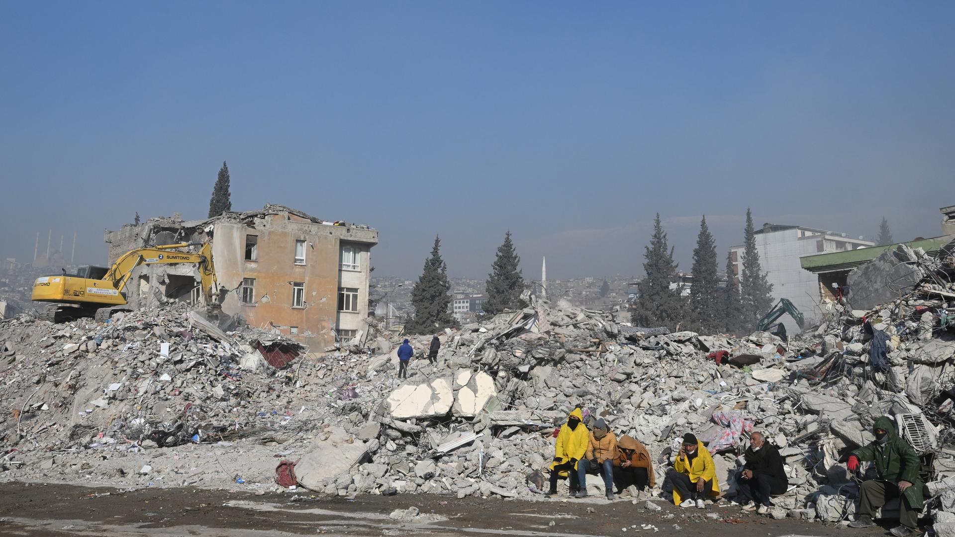 Rettungskräfte sitzen nach dem Erdbeben in der Türkei vor zerstörten Häusern.