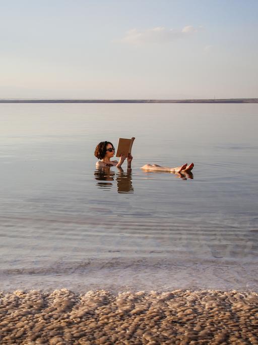 Eine Frau liest ein Buch im Toten Meer in Jordanien.