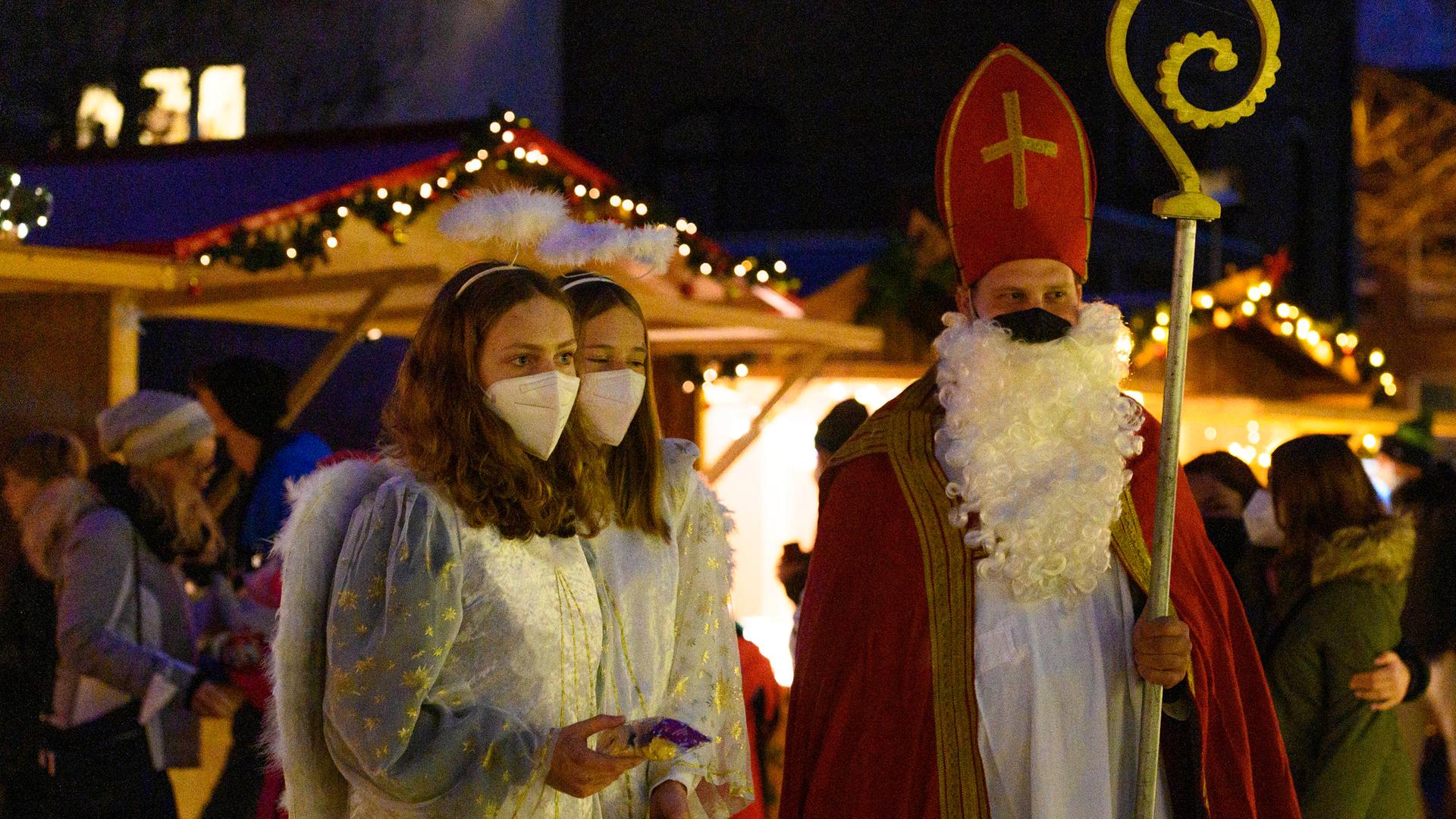 Weihnachtsengel und Weihnachtsmann mit Corona-Masken auf dem Königsdorfer Weihnachtsmarkt hinter der St. Sebastianus Kirche