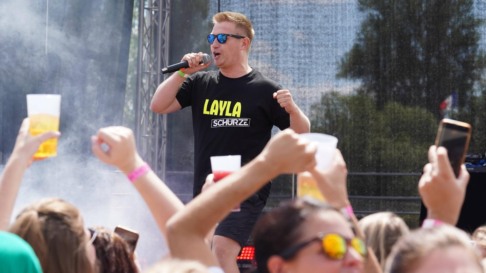 Ein Mann auf einer Bühne, davor Publikum mit Bierbechern in den Händen: Schürze mit "Layla" auf der Mallorca-Live-Party 2022 in Bad Kreuznach. Ein Mann auf einer Bühne, davor Publikum mit Bierbechern in den Händen: Schürze mit "Layla" auf der Mallorca-Live-Party 2022 in Bad Kreuznach.