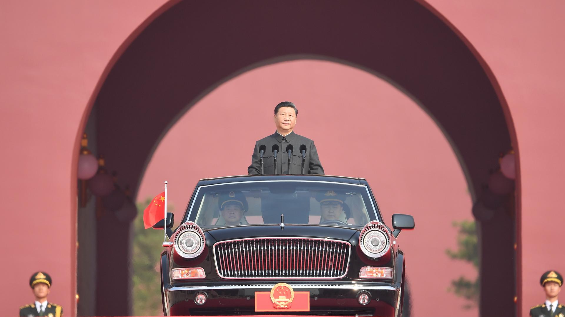 Der chinesische Staatspräsident Xi Jingping wird in einer offenen, schwarzen Limousine stehend von zwei Fahrern gefahren Der chinesische Staatspräsident Xi Jingping wird in einer offenen, schwarzen Limousine stehend von zwei Fahrern gefahren