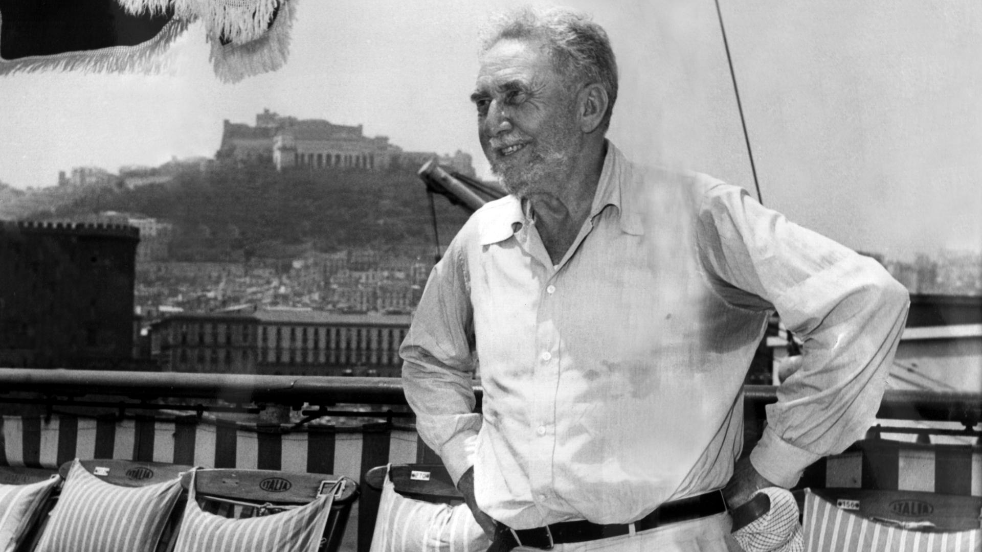 Der Schriftsteller Ezra Pound im Alter von 73 Jahren in Neapel. Er trägt Bart, ein helles Hemd und eine weiße Hose.