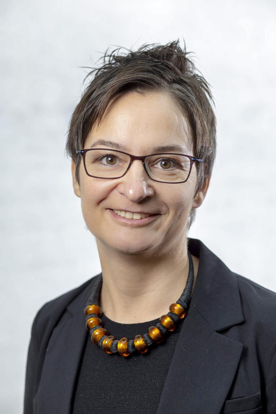 Porträtaufnahme der Soziologin Kristina Stoeckl, im Sakko mit Brille und kurzen dunklen Haaren