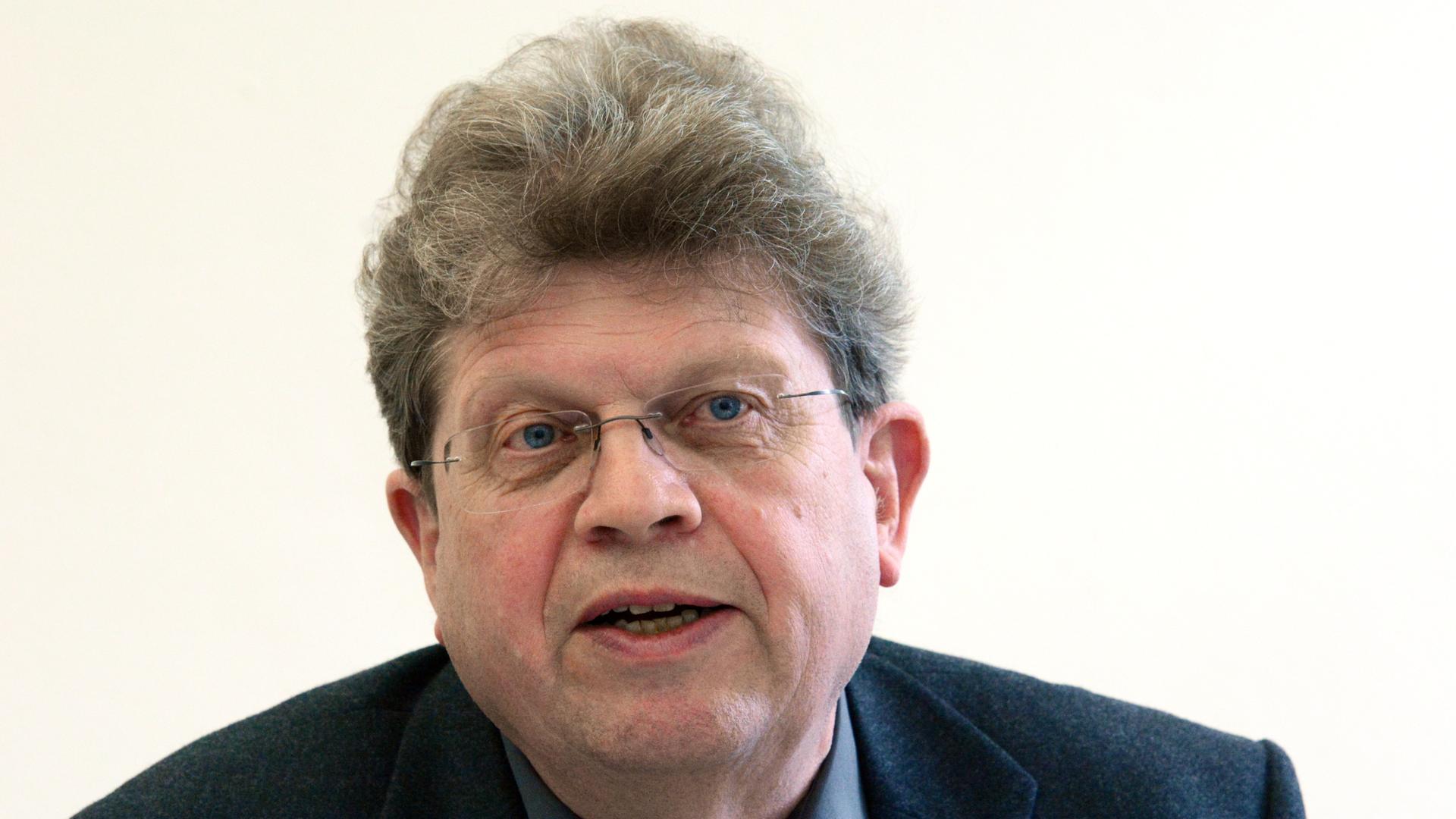 Der Immunologe Andreas Radbruch im Gespräch. Er blickt in die Kamera. Er trägt einen dunklen Anzug, eine grüne Krawatte und eine randlose Brille. Der Immunologe Andreas Radbruch im Gespräch. Er blickt in die Kamera. Er trägt einen dunklen Anzug, eine grüne Krawatte und eine randlose Brille.