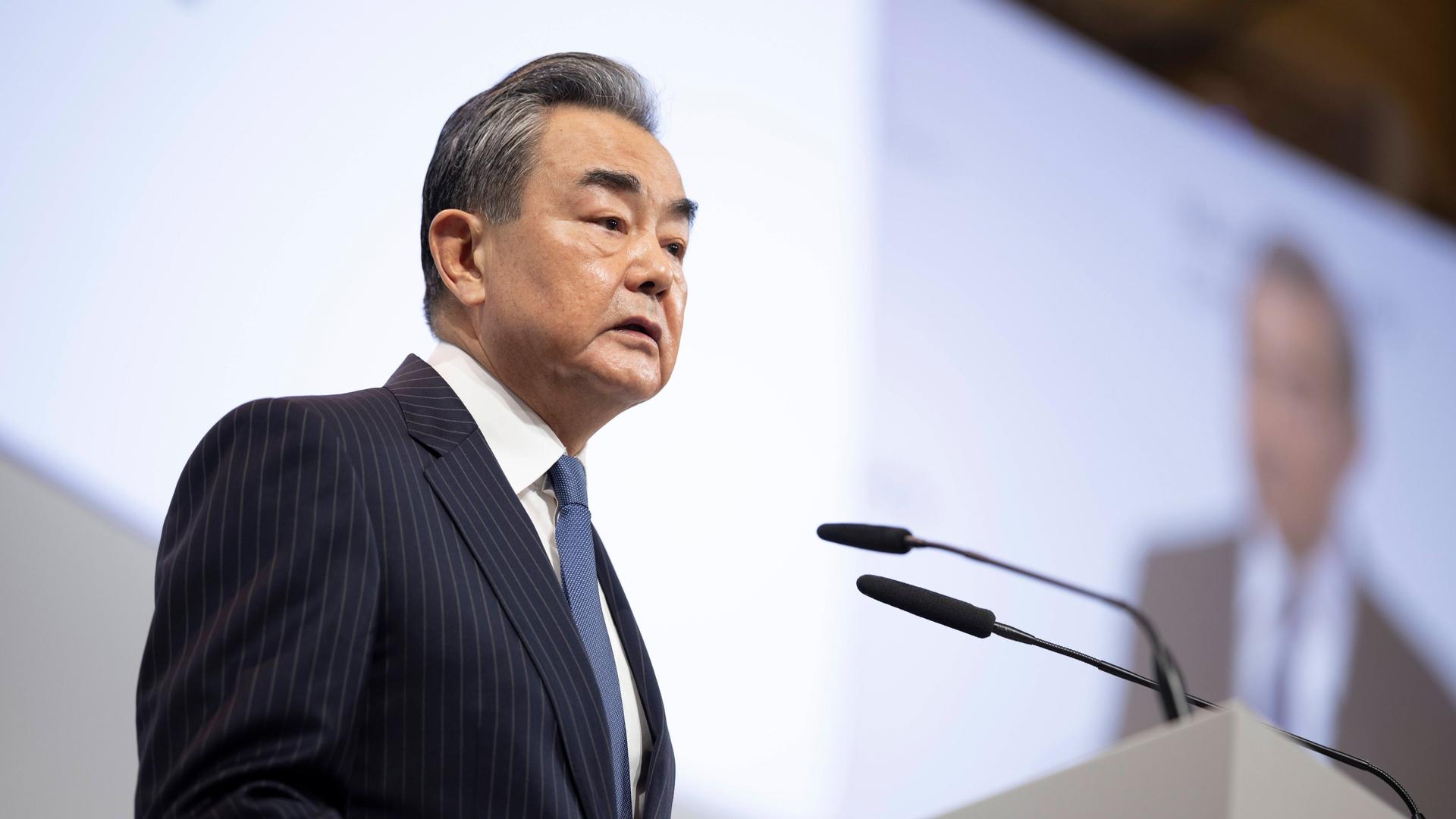 Der chinesische Außenpolitiker Wang Yi spricht bei der Münchner Sicherheitskonferenz 2023 an einem Redepult mit Mikrofonen. Über ihm ist eine Videoübertragung seiner Rede zu sehen. Der chinesische Außenpolitiker Wang Yi spricht bei der Münchner Sicherheitskonferenz 2023 an einem Redepult mit Mikrofonen. Über ihm ist eine Videoübertragung seiner Rede zu sehen.