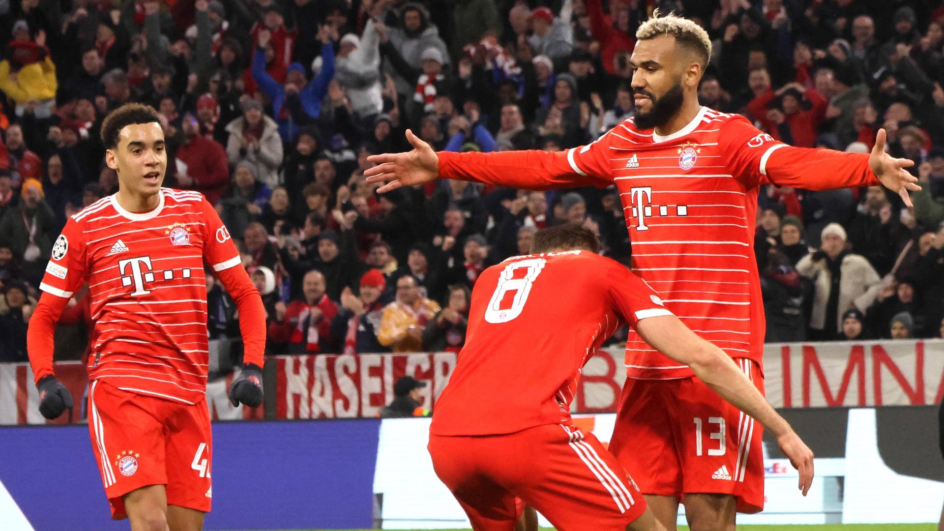 Drei Spieler von Bayern München jubeln über ein Tor. Zwei von ihnen umarmen sich. Sie stehen auf dem Fußball-Rasen. Im Hintergrund sind Zuschauer. Drei Spieler von Bayern München jubeln über ein Tor. Zwei von ihnen umarmen sich. Sie stehen auf dem Fußball-Rasen. Im Hintergrund sind Zuschauer.