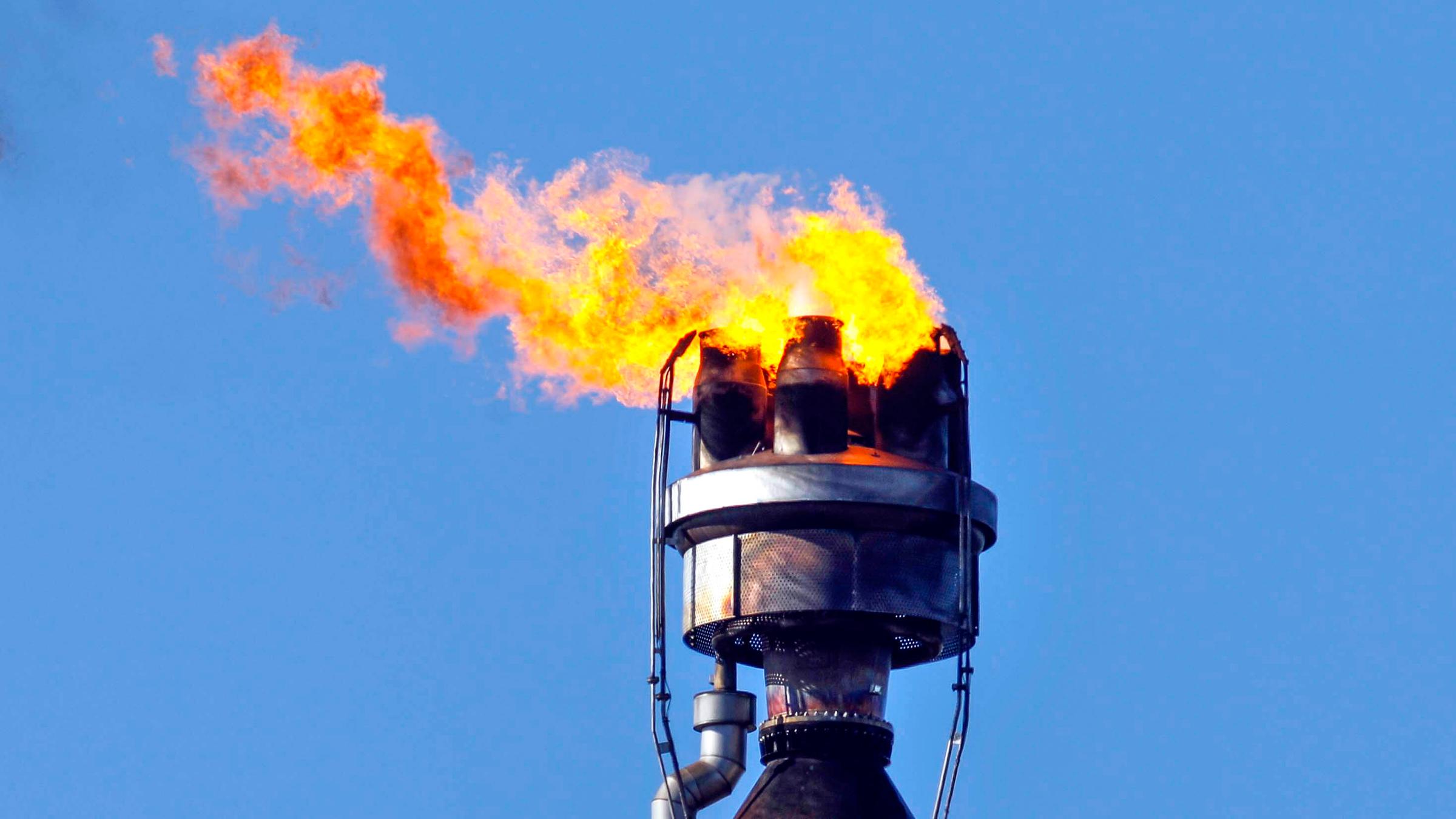 Eine Flamme brennt an einem Schornstein einer Ölraffinerie.