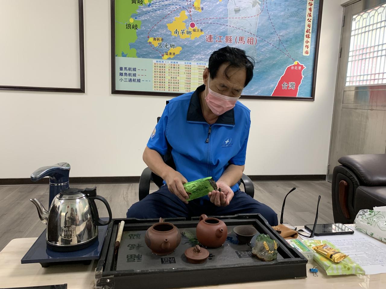 Schiffsunternehmer Chen Kai-shous bereitet in seinem Büro eine Kanne Tee zu. Hinter ihm ist eine Seekarte zu sehen mit den Strecken seiner Schiffe zwischen Taiwan und den Matsu-Inseln.