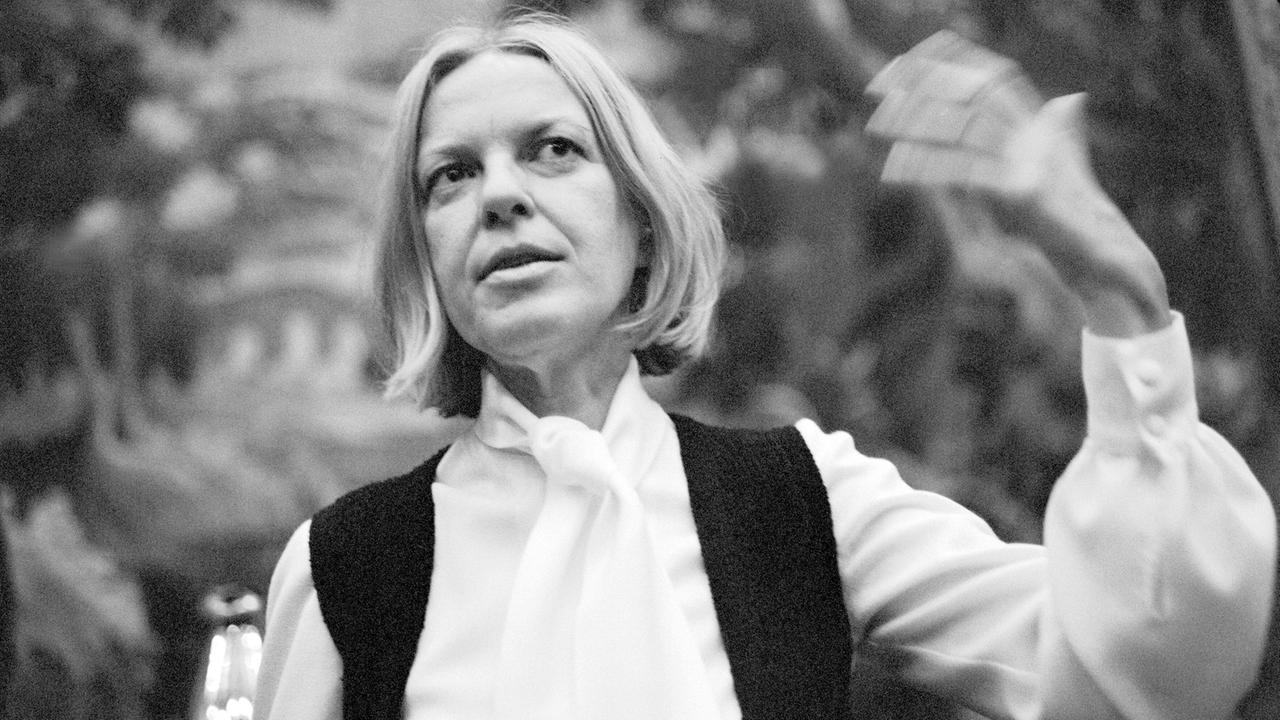 Ingeborg Bachmann steht in einem Garten und gestikuliert mit ihrer linken Hand in der Luft. Die Mittvierzigerin trägt auf dem Schwarz-Weiß-Bild eine helle Bluse und eine dunkle Weste darüber, ihre schulterlangen Haare sind gescheitelt. Ingeborg Bachmann steht in einem Garten und gestikuliert mit ihrer linken Hand in der Luft. Die Mittvierzigerin trägt auf dem Schwarz-Weiß-Bild eine helle Bluse und eine dunkle Weste darüber, ihre schulterlangen Haare sind gescheitelt.