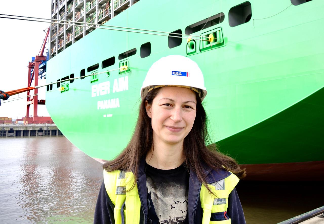 Kranfahrerin Franziska Reisener steht vor dem Megafrachter "Ever Aim" im Hamburger Hafen