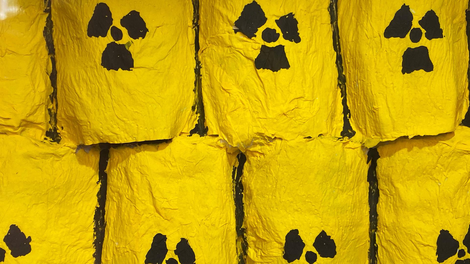 Gelbe Fässer mit dem schwarzen Zeichen für Atommüll stehen übereinander gestapelt.