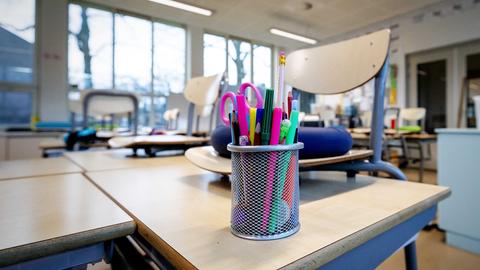 Blick in ein leeres Klassenzimmer mit Stühlen auf den Tischen 