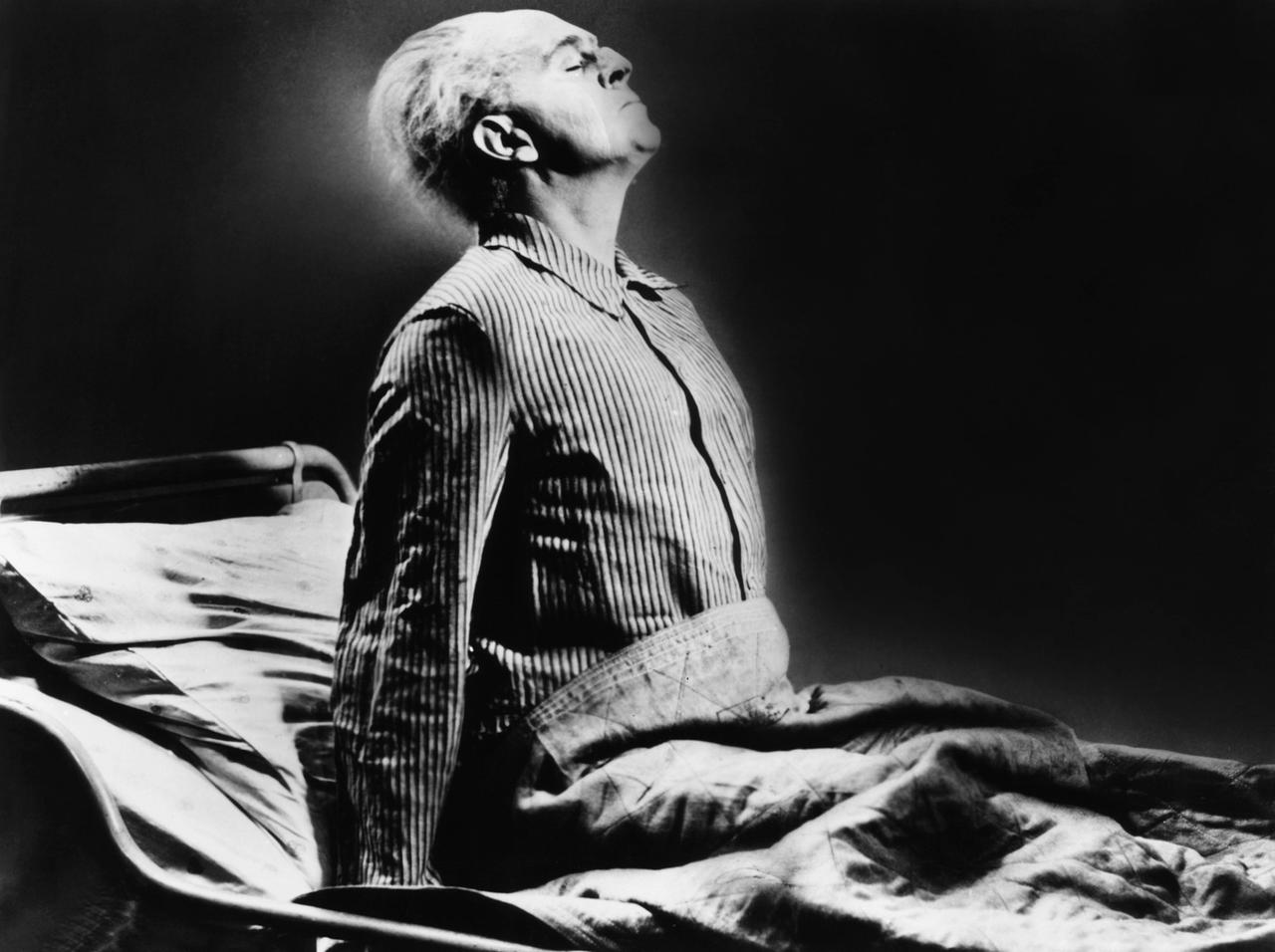 Im Filmstill aus "Das Testament des Dr. Mabuse" sitzt Dr. Mabuse (Rudolf Klein-Rogge) aufrecht und mit weggetretenem Gesichtsausdruck in seinem Bett.