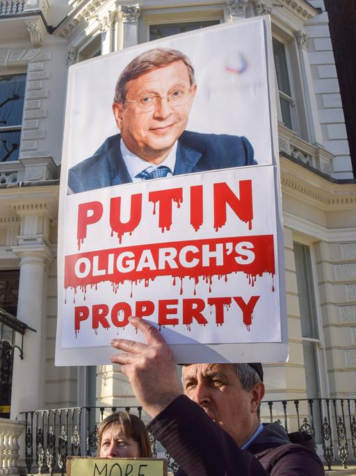 Ein Demonstrant in London hält ein Plakat hoch, dass den russischen Oligarchen Wladimir Jewtuschenkow zeigt. 