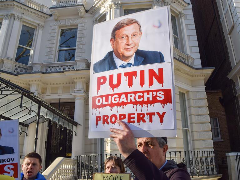 Ein Demonstrant in London hält ein Plakat hoch, dass den russischen Oligarchen Wladimir Jewtuschenkow zeigt. 