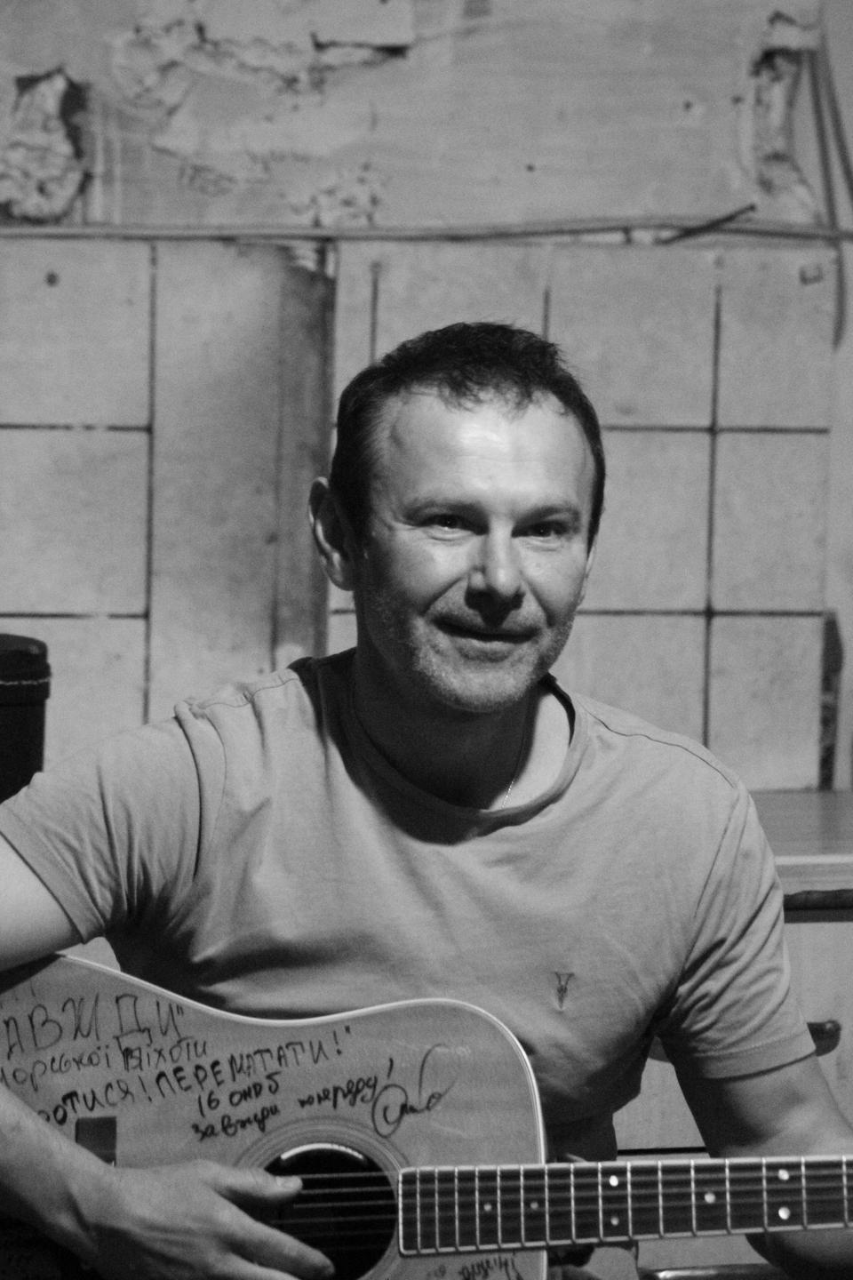 Der Sänger Warkatschuk hält eine Gitarre in der Hand, auf die ukrainische Einheiten Grüße geschrieben haben. Der Sänger Warkatschuk hält eine Gitarre in der Hand, auf die ukrainische Einheiten Grüße geschrieben haben.