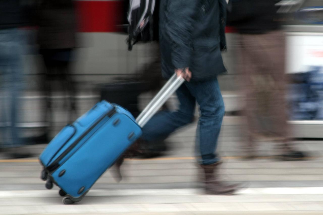Ein Mann mit Rollkoffer eilt über einen Bahnsteig. Ein Mann mit Rollkoffer eilt über einen Bahnsteig.