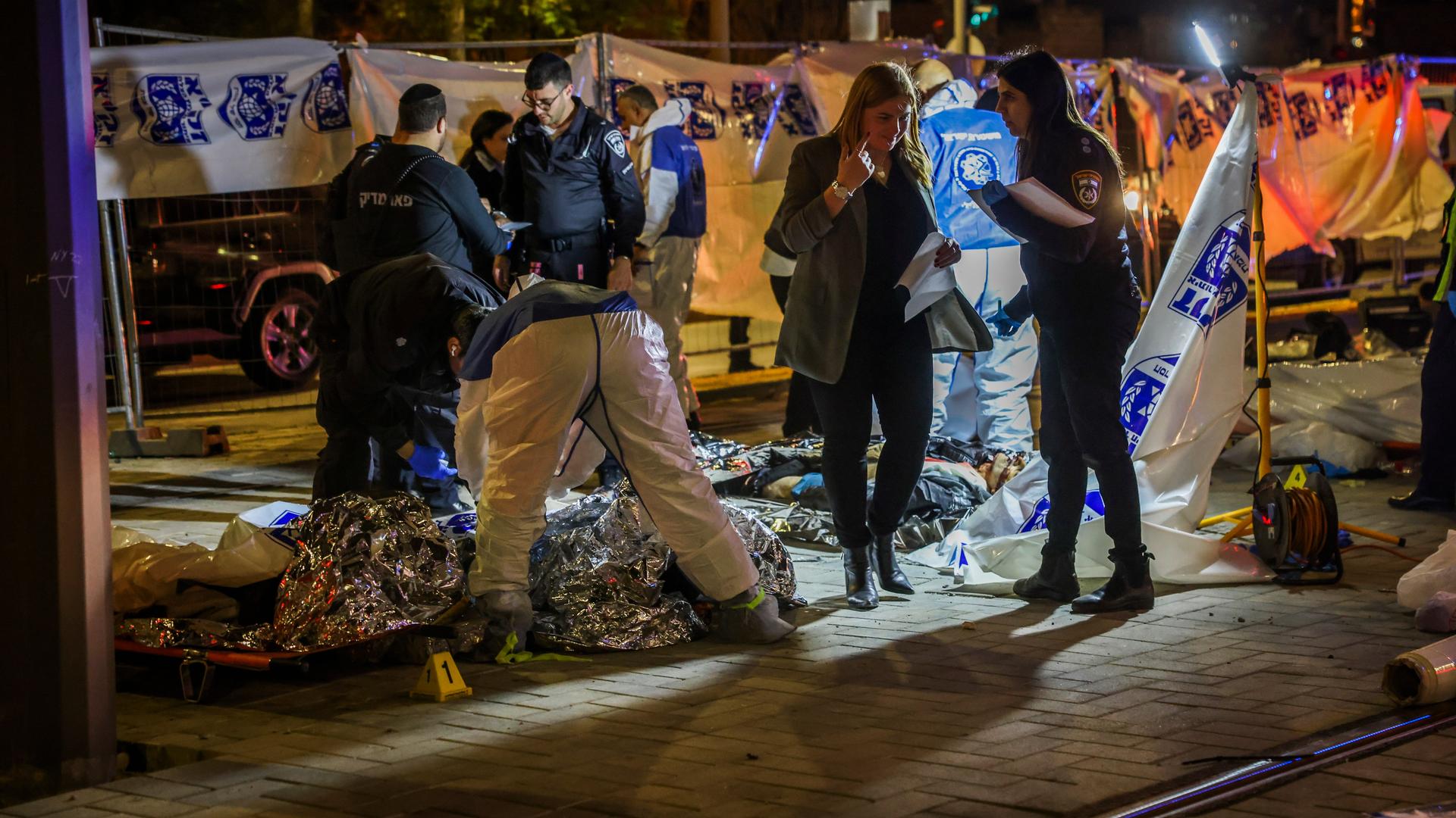 Das Bild zeigt Rettungskräfte in der Nacht und Opfer, die in Folien eingewickelt sind. Das Bild zeigt Rettungskräfte in der Nacht und Opfer, die in Folien eingewickelt sind.