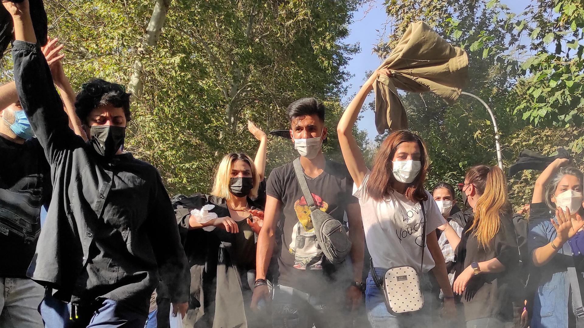 Iranische Demonstranten setzen ihre Schals in Brand, während sie am 1. Oktober 2022 in Teheran eine Straße entlang marschieren. Das Bild wurde mit einer Handykamera aufgenommen. 