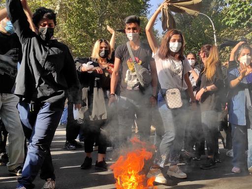 Iranische Demonstranten setzen ihre Schals in Brand, während sie am 1. Oktober 2022 in Teheran eine Straße entlang marschieren. Das Bild wurde mit einer Handykamera aufgenommen. 