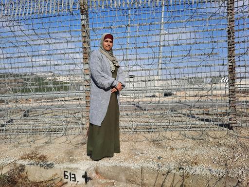 Eine Frau steht vor einem Zaun.