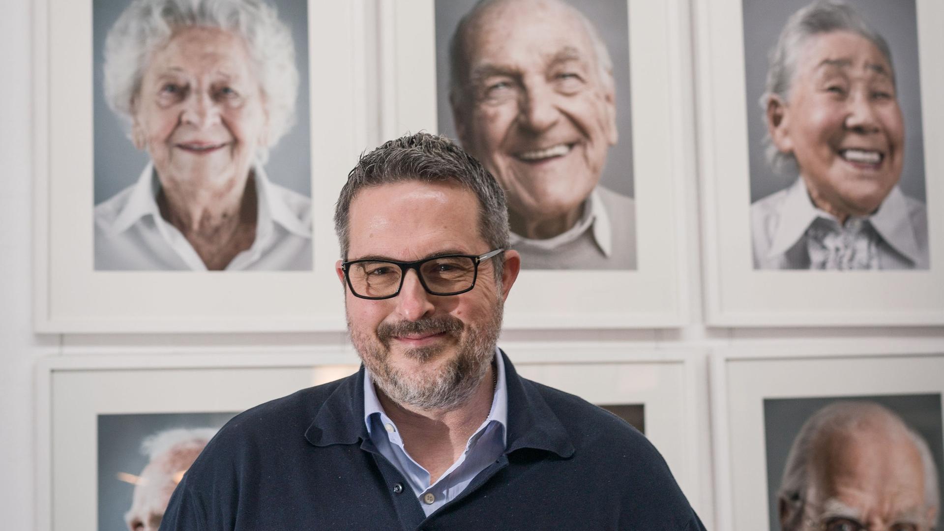 Der Fotograf Karsten Thormaehlen steht mit seinem Buch "Hundert Jahre Lebensglück" vor Fotos von Menschen, die das 100.Lebensjahr erreicht haben und die er porträtiert hat. Der Fotograf Karsten Thormaehlen steht mit seinem Buch "Hundert Jahre Lebensglück" vor Fotos von Menschen, die das 100.Lebensjahr erreicht haben und die er porträtiert hat.
