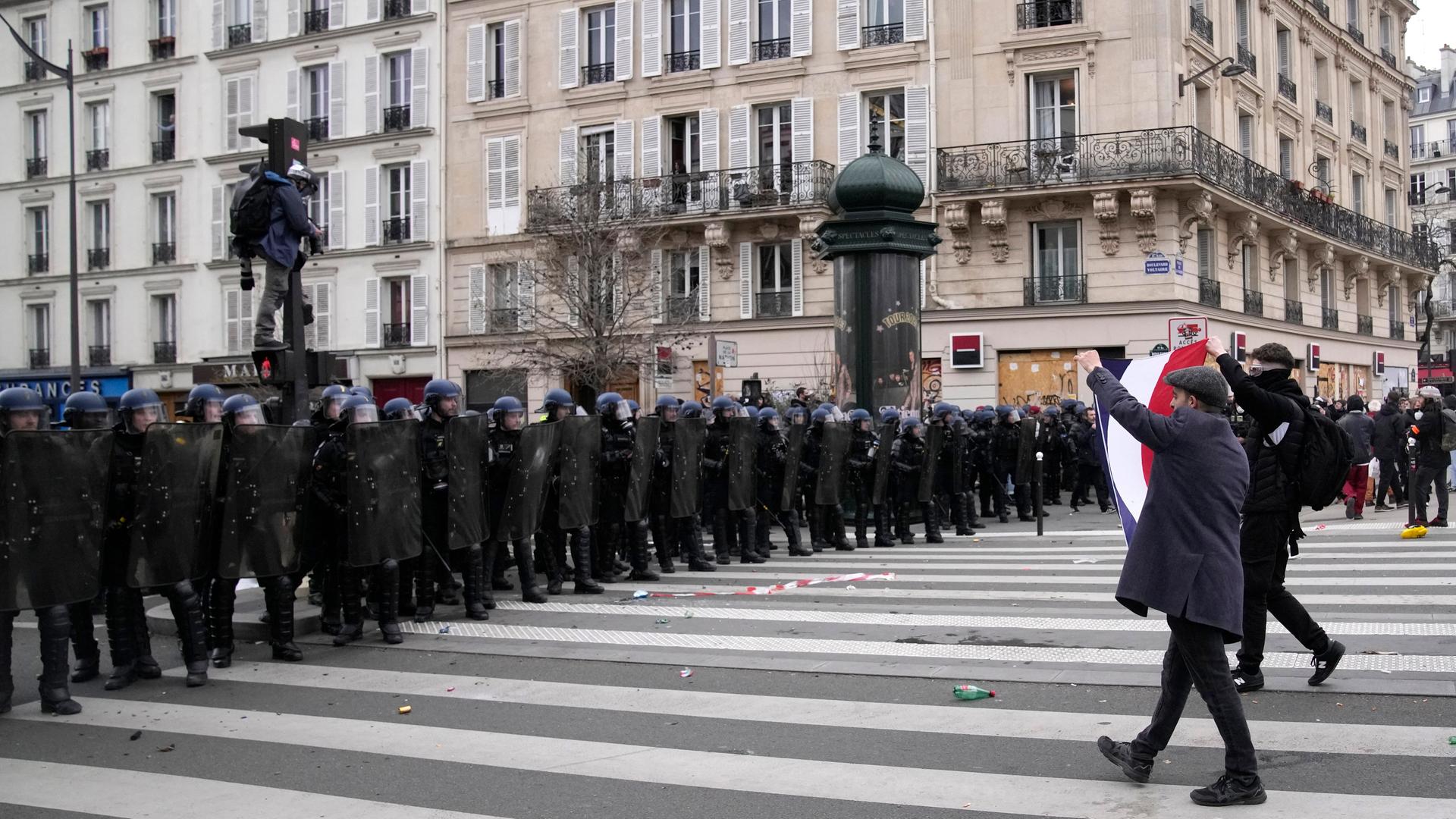 Polizisten in einer geschlossenen Reihe stehen in Paris Demonstranten gegenüber. Polizisten in einer geschlossenen Reihe stehen in Paris Demonstranten gegenüber.