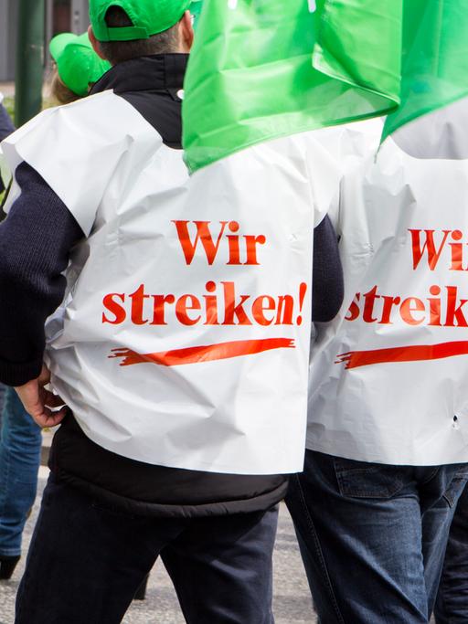 Personen mit Westen auf denen "Wir streiken" steht demonstrieren für Lohnerhöhungen.