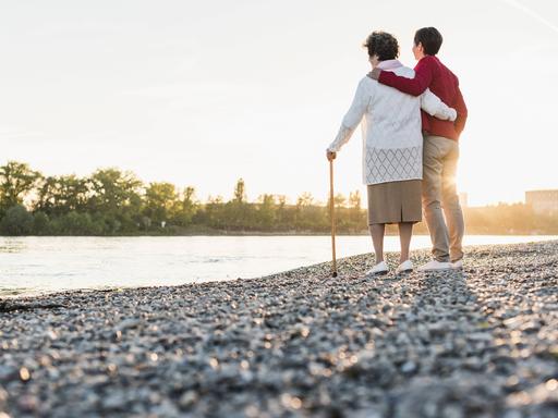 Eine alte und eine jüngere Frau stehen an am Strand und schauen aufs Wasser raus. Eine alte und eine jüngere Frau stehen an am Strand und schauen aufs Wasser raus.