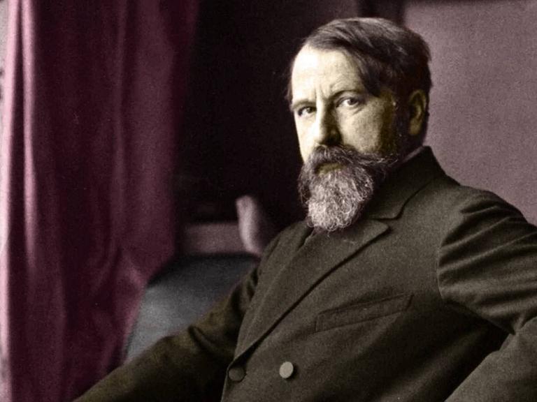 Porträt von 1900: Arthur Schnitzler im Anzug, in selbstbewusster Pose mit der Hand in die Hüfte gestemmt.
