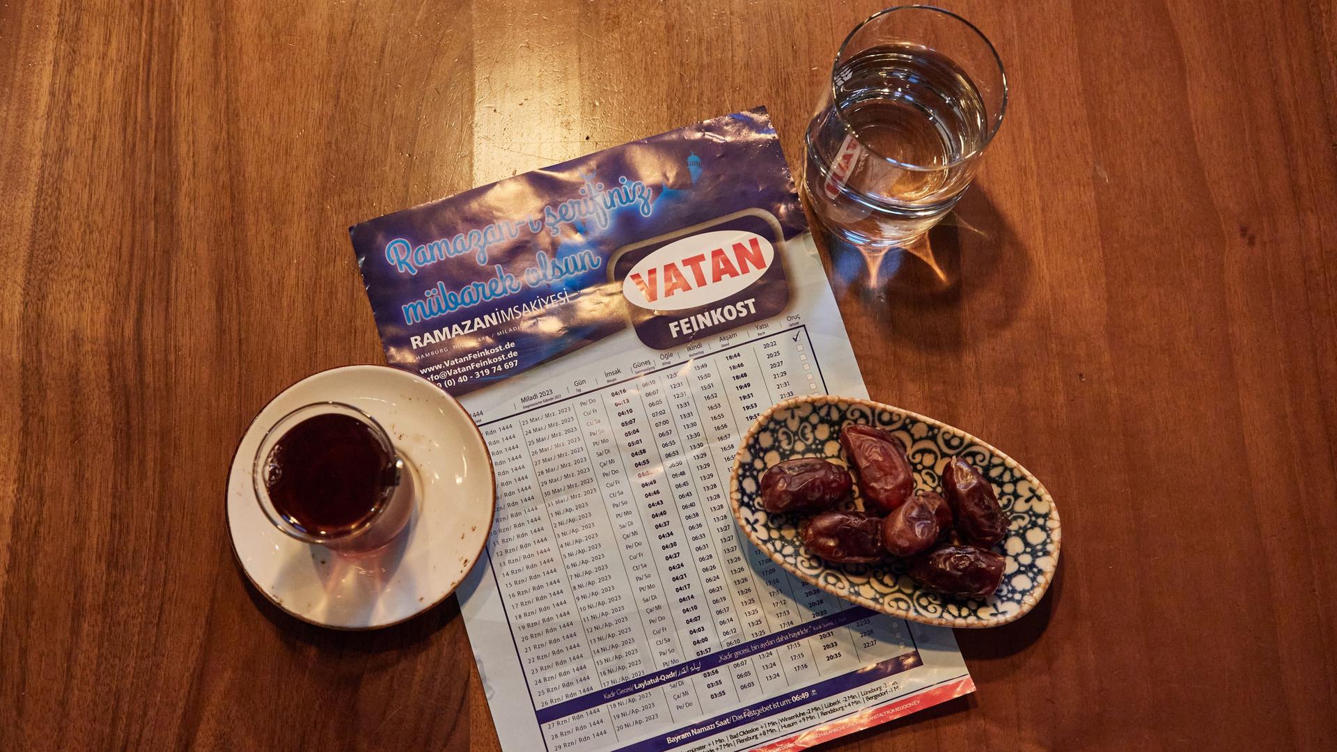 Ein Glas Wasser, ein Glas Tee, ein Schale mit Datteln und der Ramadan-Kalender mit den Uhrzeiten stehen im Restaurant Pamukkale Köz auf dem Tisch