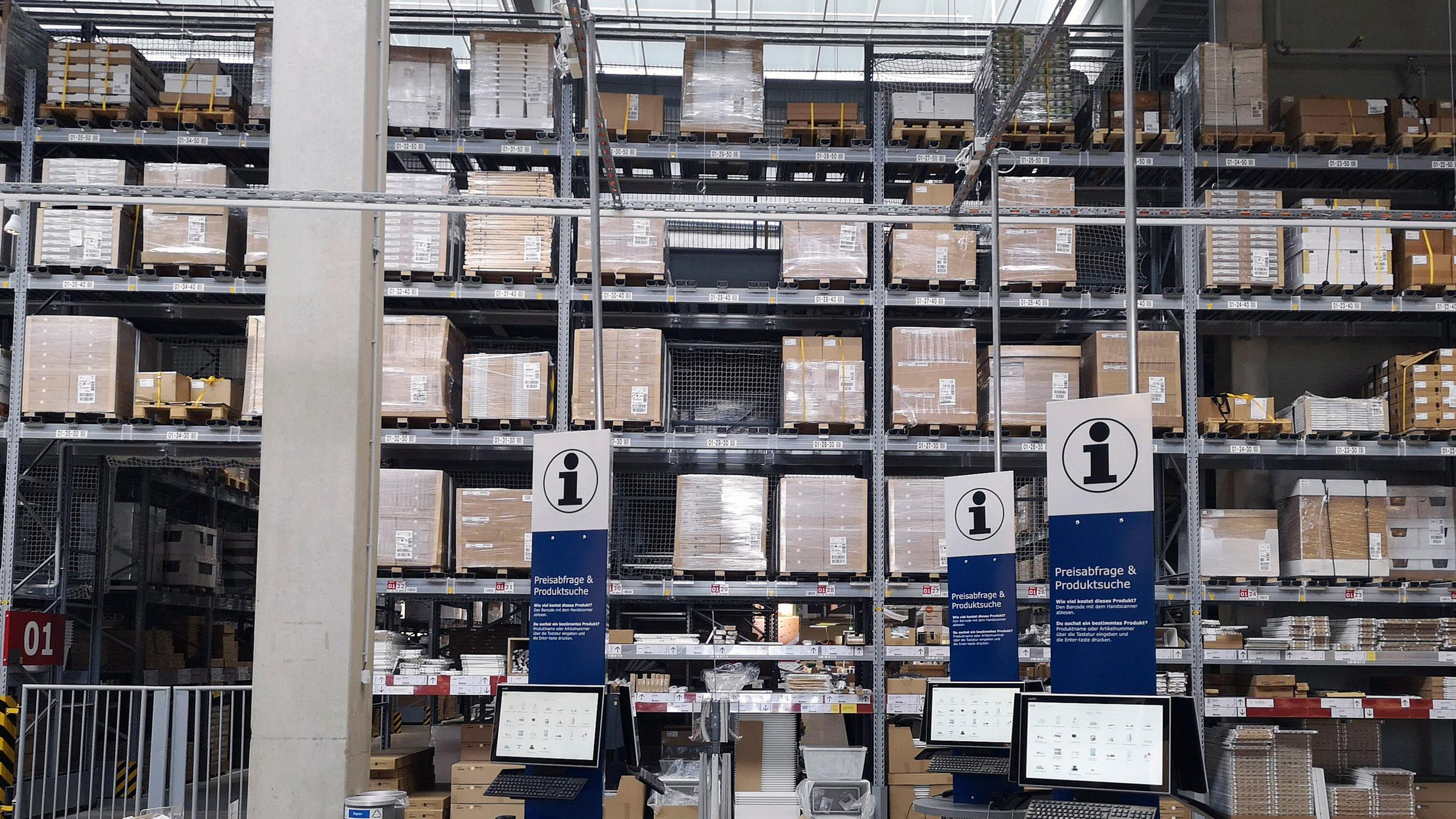 Auf dem Foto vom Ikea Einrichtungshaus in Kaarst sind im Vordergrund Infoterminals zu sehen, im Hintergrund ein Hochlager voller Kartons und Verpackungen.