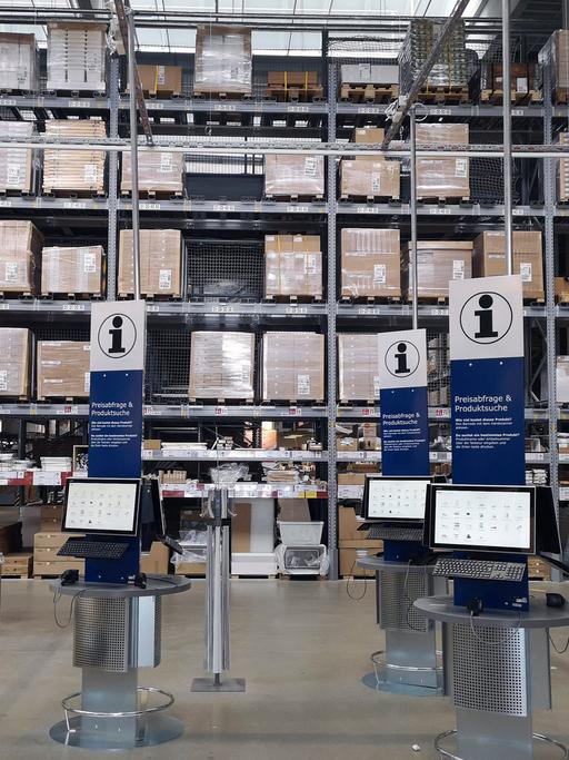 Auf dem Foto vom Ikea-Einrichtungshaus in Kaarst sind im Vordergrund Infoterminals zu sehen, im Hintergrund ein Hochlager voller Kartons und Verpackungen.