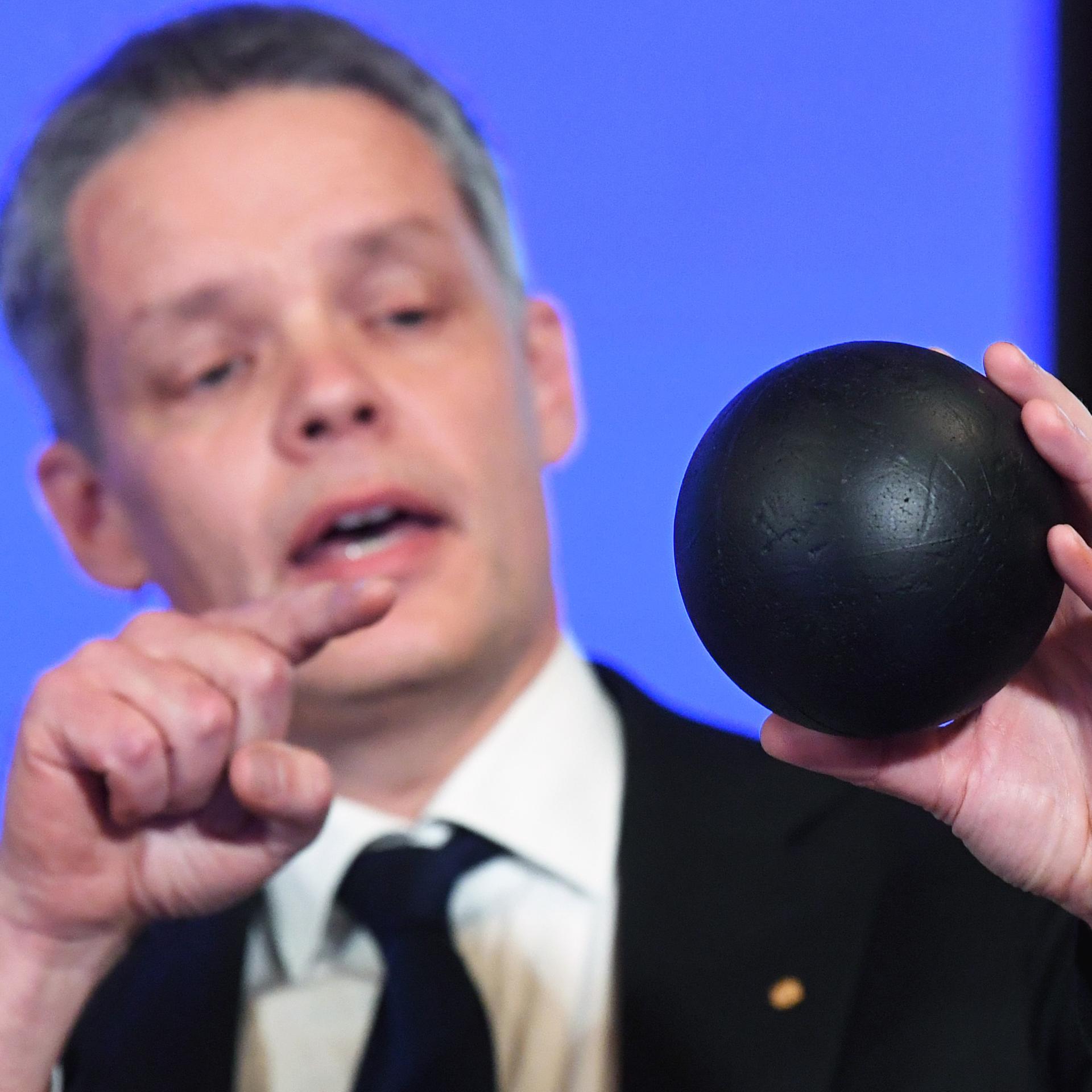 Der Physiker Ulf Danielsson blickt auf eine schwarze Kugel in seiner Hand und erklärt anhand dieses Modells eine Theorie