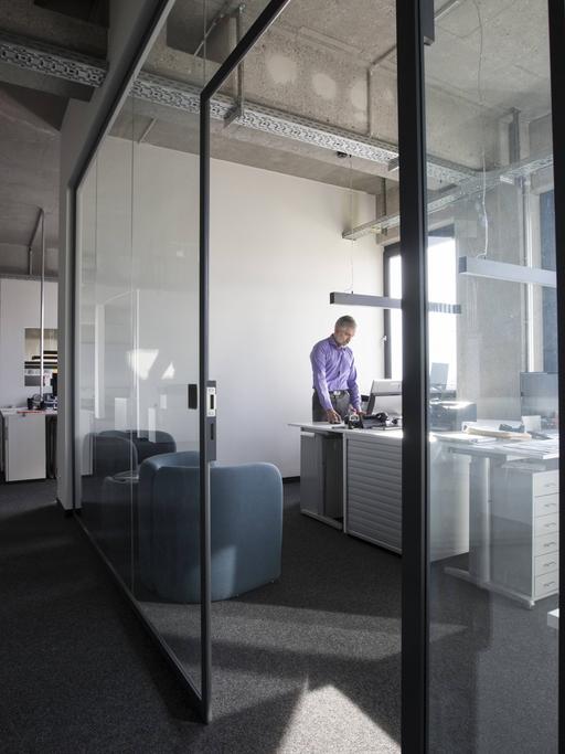 Ein Geschäftsmann allein in einem Büro mit Glastüren auf einer Büroetage