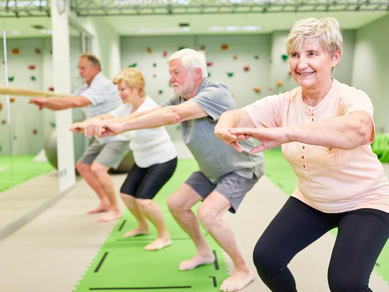 Senioren machen Kniebeugen für Kraft und Motorik.