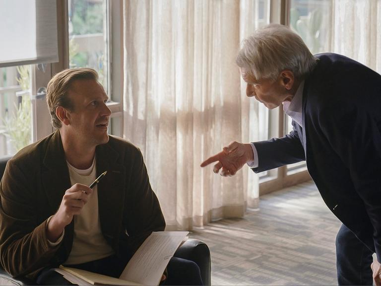 Szene aus der US-Serie "Shrinking" auf AppleTV+: Ein Mann (Jason Segel) sitzt in einem Sessel, ein älterer Mann (Harrison Ford) redet stehend auf ihn ein. 