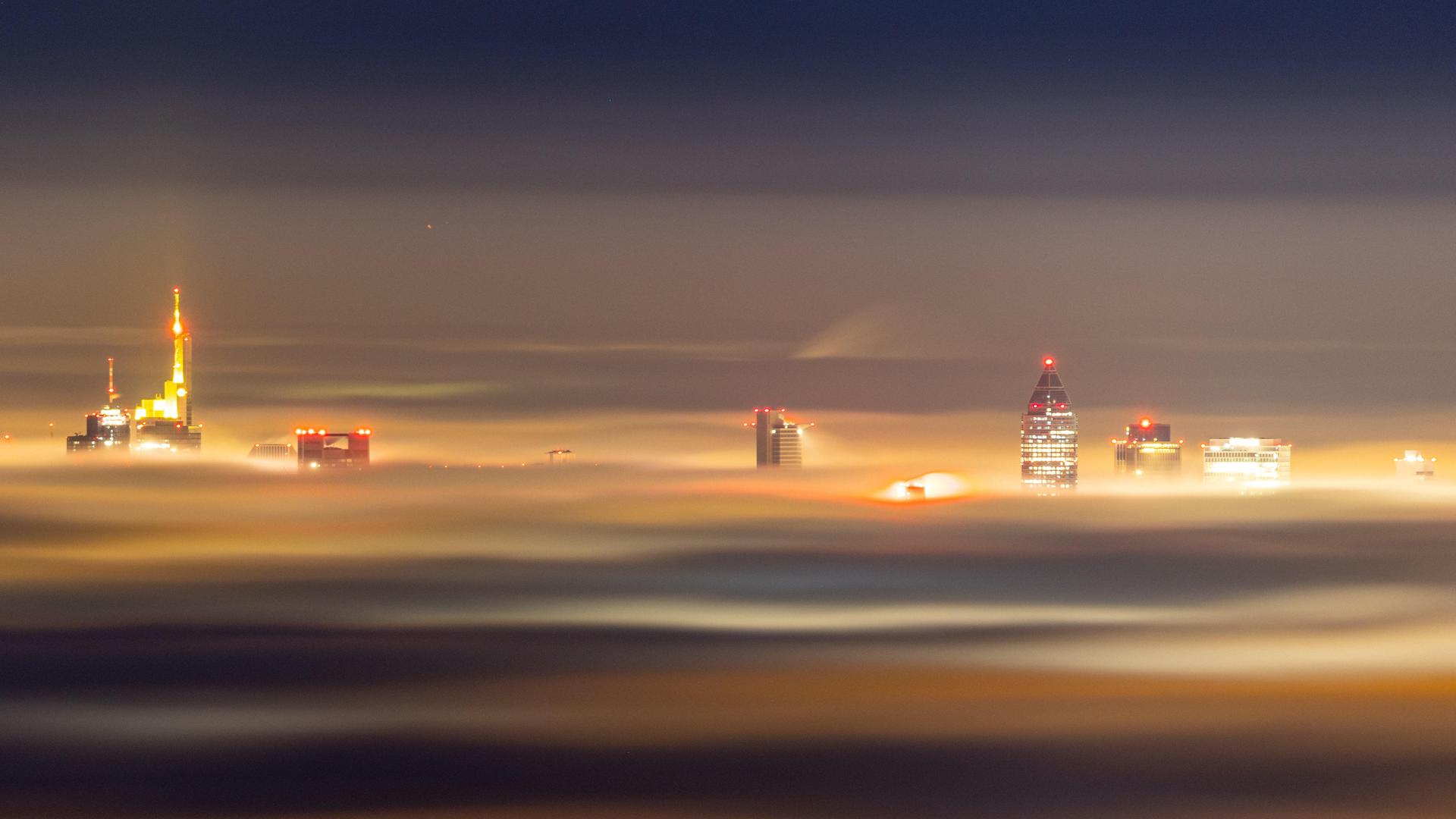 Die Hochhäuser der Frankfurter Bankenskyline ragen am Abend aus einem Nebelmeer über dem Rhein-Main-Gebiet.