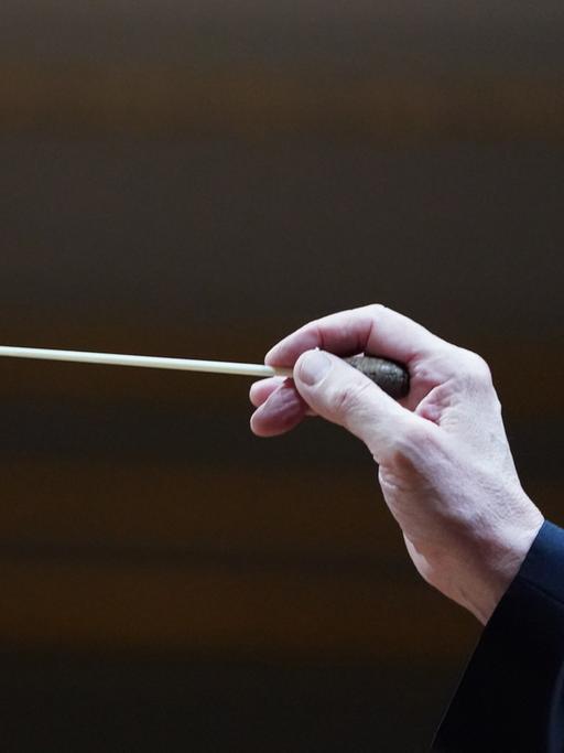 Die Hand eines Dirigenten mit dem Taktstock. 