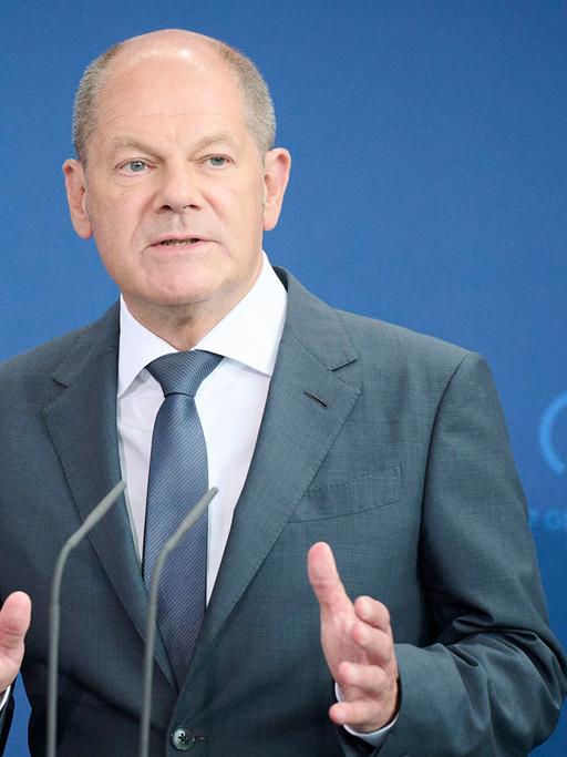 Bundeskanzler Scholz steht hinter zwei Mikrofonen und gestikuliert.
