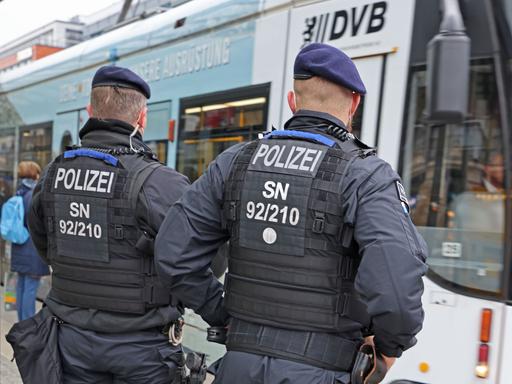 Zwei Polizisten stehen vor einer Straßenbahn in Dresden