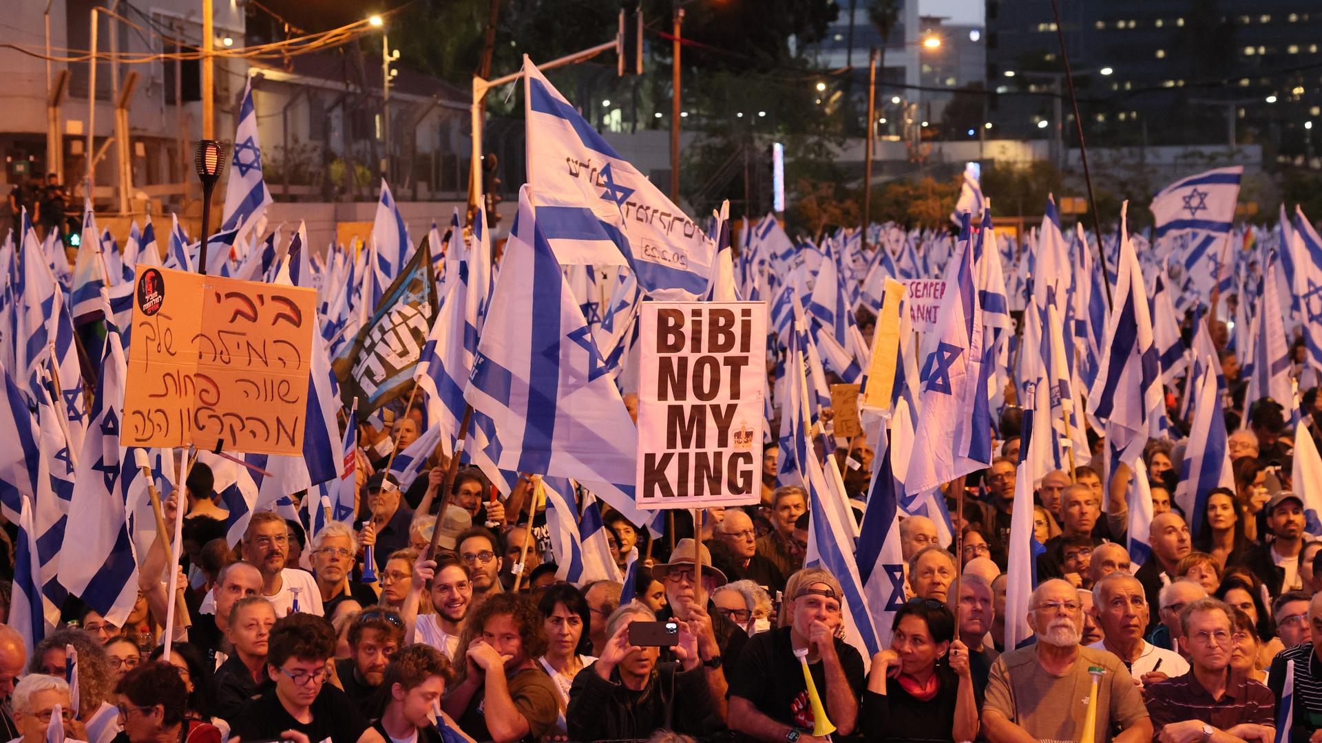 Demonstranten stehen eng beeinander und halten Plakate hoch. Darauf steht übersetzt "Bibi ist nicht mein König". Demonstranten stehen eng beeinander und halten Plakate hoch. Darauf steht übersetzt "Bibi ist nicht mein König".