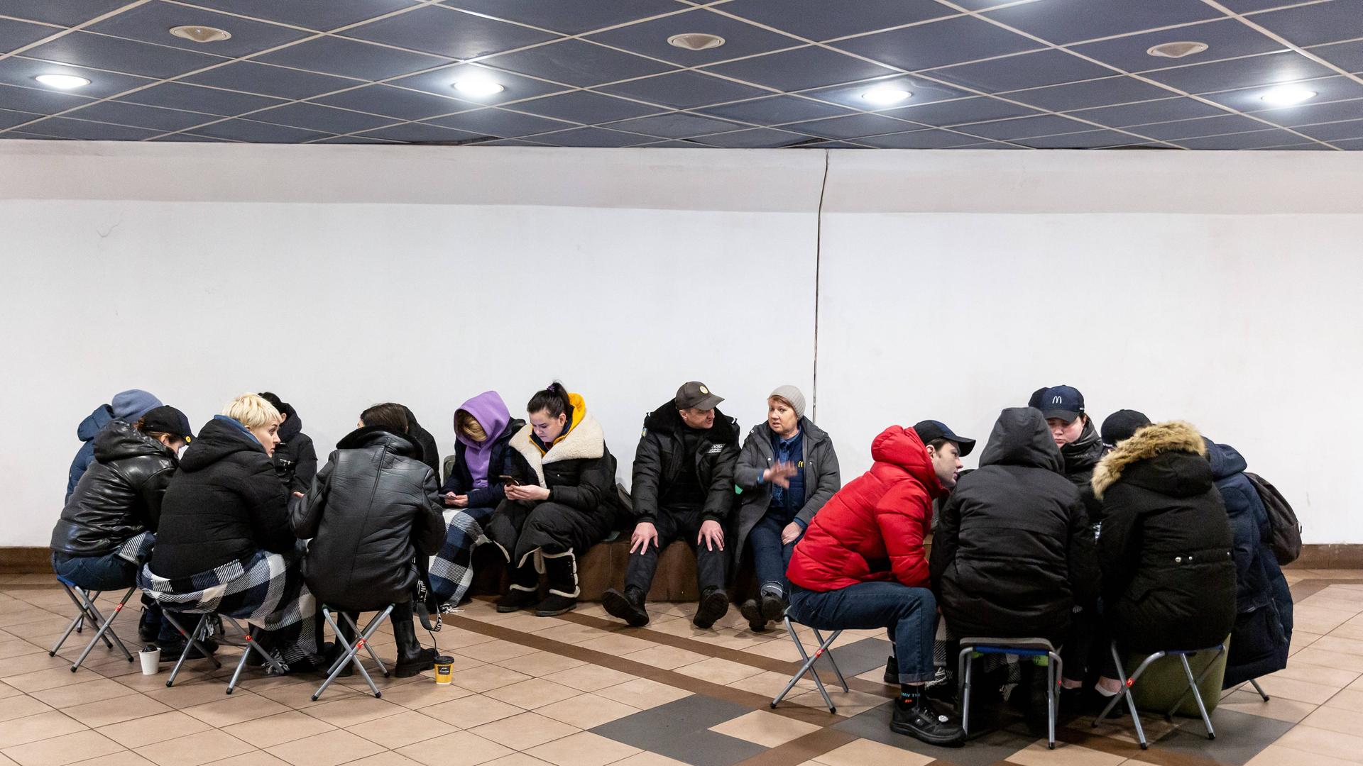 Nach einem Bombenalarm in Kiew suchen Menschen Schutz in einer Metro-Station. Menschen sitzen zusammen und unterhalten sich. Nach einem Bombenalarm in Kiew suchen Menschen Schutz in einer Metro-Station. Menschen sitzen zusammen und unterhalten sich.