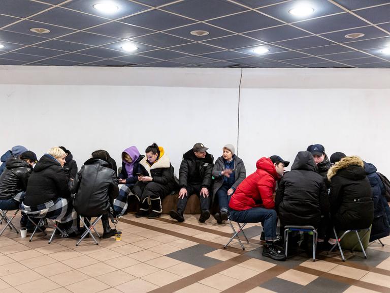 Nach einem Bombenalarm in Kiew suchen Menschen Schutz in einer Metro-Station. Menschen sitzen zusammen und unterhalten sich.