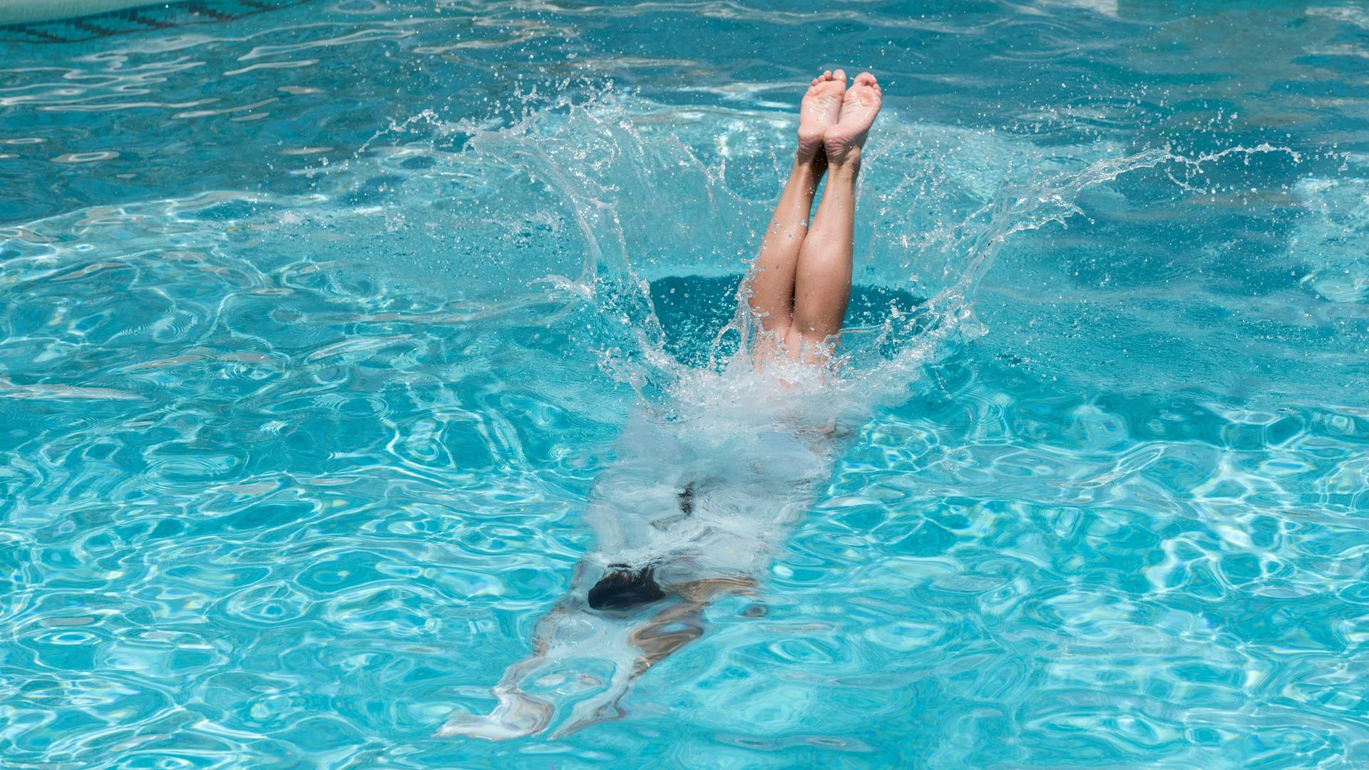 Beine kurz vorm Eintauchen ins Wasser, nach dem Kopfsprung in einen Pool. 