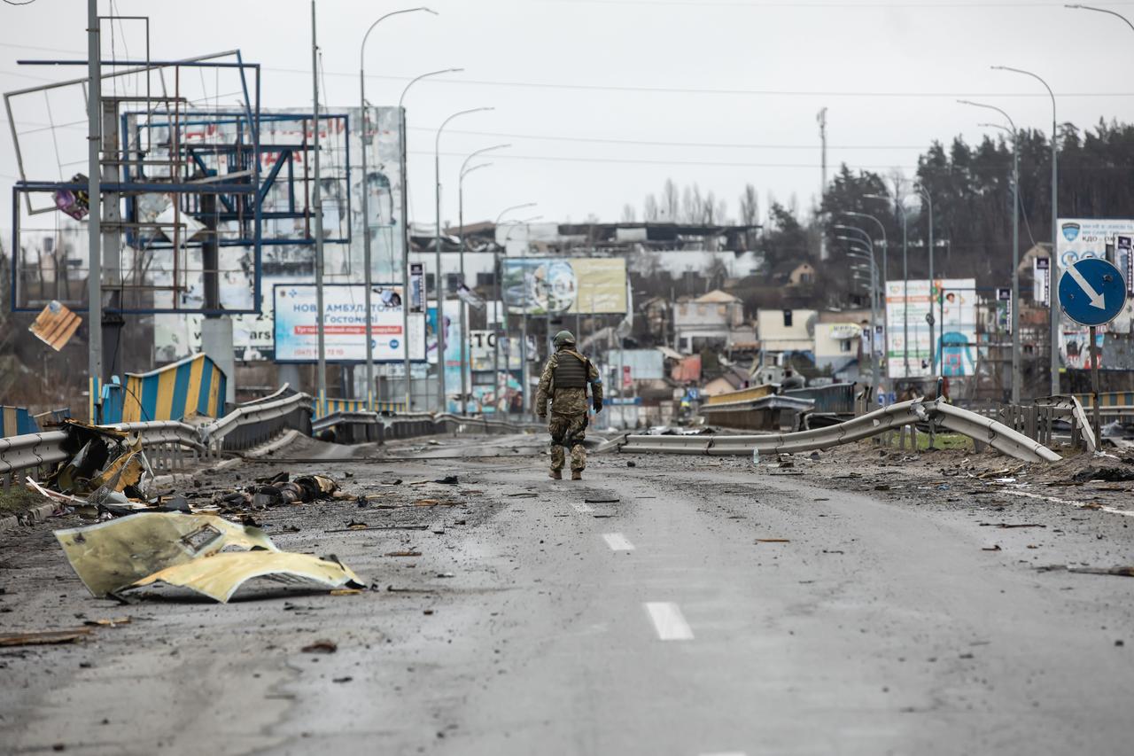 Ein ukrainischer Soldat geht auf einer zerstörten Straße in Butscha. 