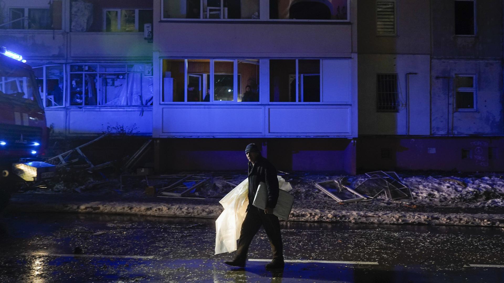 Folgen des russischen Beschusses in der Stadt Wyschhorod: Eine Person trägt Habseligkeiten eine dunkel Straße entlang. Folgen des russischen Beschusses in der Stadt Wyschhorod: Eine Person trägt Habseligkeiten eine dunkel Straße entlang.